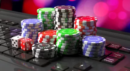 Casino chips and dice stacked up on a laptop
