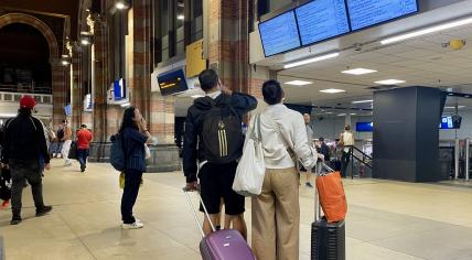 People with suitcases at Amsterdam Centraal trying to find information about their train. 5 September 2024