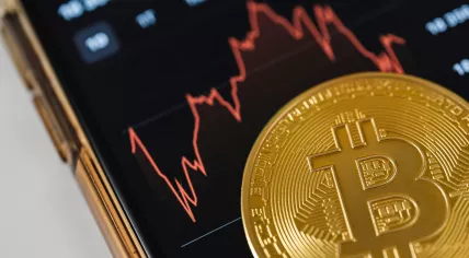 Close-up of a Bitcoin Coin Lying on a Screen Displaying a Stock Market Chart