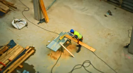 A worker cutting wood on a bench in a workshop