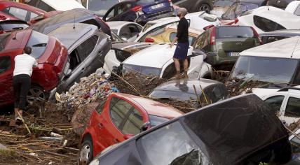 Residents look at cars piled up after being swept away by floods in Valencia, Spain, Wednesday, Oct. 30, 2024.