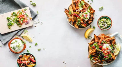 A collection of ingredients, including a salad, guacamole, spring onions, tomatoes, red onions, sour cream, and sweet potato fries. 12 November 2018