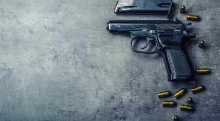Pistol gun and discharged bullets on the table