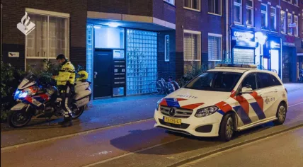A Dutch police officer, car and motorcycle on an Amsterdam street at night