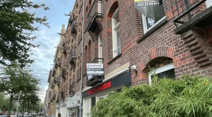 A woman walks by two homes for sale on the Javastraat in Amsterdam-Oost in July 2023.