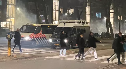  People cross in front of a police tactical van and a riot police unit van in Amsterdam-Oost, December 31, 2024.