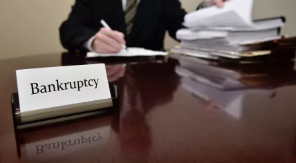 A bankruptcy administrator sitting at a desk with a big pile of papers