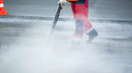 Worker uses a pressure washer to clean the streets.
