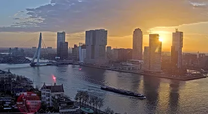 The sun rises over the Erasmus Bridge, De Rotterdam, and the Cruise Terminal along the Nieuwe Maas River and the Kop van Zuid in Rotterdam. 7 Mar 2025