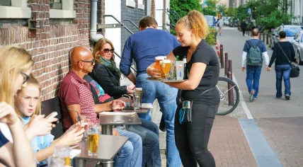 A waitress brings drinks to a customer on a terrace in Amsterdam