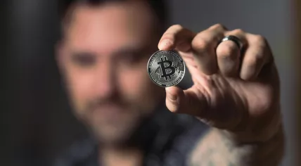 A man holding a coin to represent Bitcoin tokens