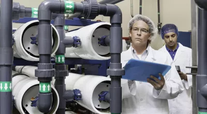 Teacher and student inspect equipment at a factory.
