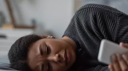 A woman looks at her phone, visibly distressed.