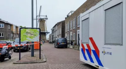 A woman was found murdered in her home on Molenstraat in Hellevoetsluis on 16 April 2025. The photo shows a mobile police unit and crime scene tape cordoning off the scene.