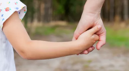 Mother and daughter hold hands.