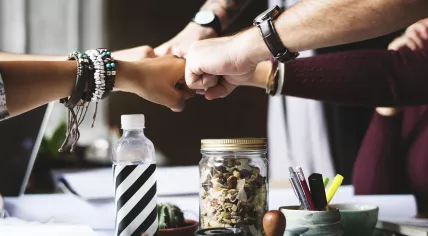 Five men and women fist bump after making a business deal