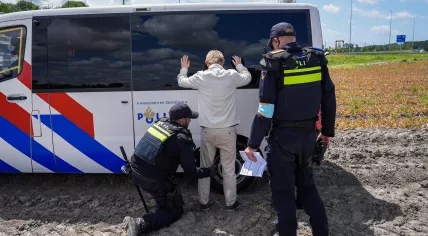 Police search a person during an Extinction Rebellion (XR) protest near the A44 highway in Abbenes, Noord-Holland.