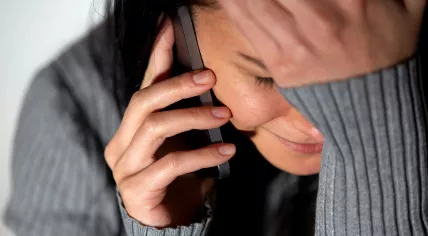A woman cries while speaking on the phone.
