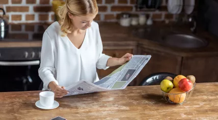 A woman is reading a newspaper.