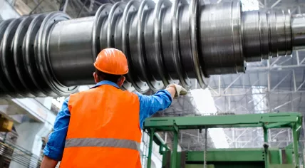 A worker in a hard hat area wearing a high visibility vest