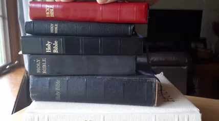 A hand upon a stack of christian bibles