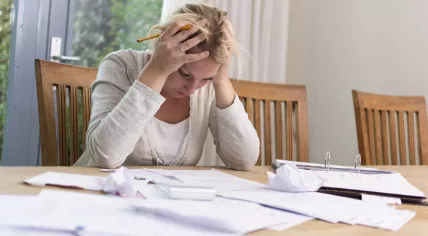 A woman works on her bills, stressed about her finances.