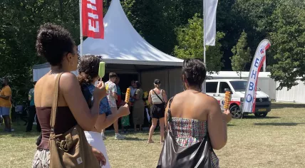 Several women walk with popsicles past a first aid tent during the National Slavery Abolitin Commemoration in Amsterdam. 1 July 2025