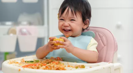 A laughing toddler is eating