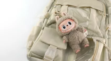Labubu Macaron collectible keychain from Pop Mart’s blind box series, hanging on an ivory backpack