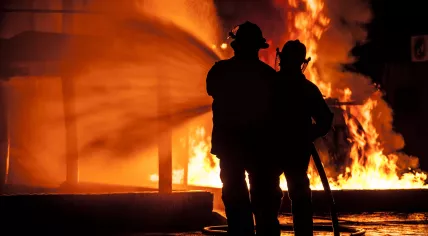 Firefighters battle large flames at a burning building.