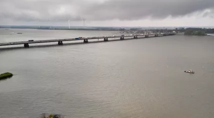 Aerial view of the Moerdijk railway and road bridges crossing the Hollands Diep under dark clouds. Tugboats, windturbines and water visible. 27 May 2025