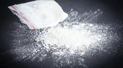 White powder spilled on a table next to a small bag containing more powder