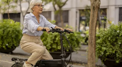 A woman is riding past urban greenery 