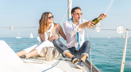 A couple is popping champagne on their yacht.