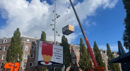 A pre-fabricated residential space being lifted over a poster for the 2025 parliamentary election to be placed as an apartment’s rear garden extension in Amsterdam, 17 October 2025