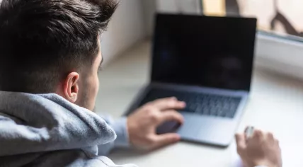 Rear view of a young man working with laptop