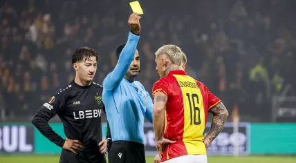 Referee Mohammed Al-Hakim shows a yellow card to Victor Edvardsen of Go Ahead Eagles and Angelo Stiller of VfB Stuttgart during the Dutch Eredivisie match between Go Ahead Eagles and VfB Stuttgart at Stadion De Adelaarshorst on November 27, 2025 in Deventer, Netherlands.