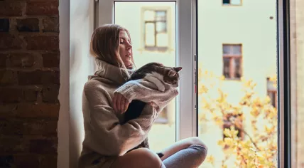 A girl and her cat sit on a windowsill 