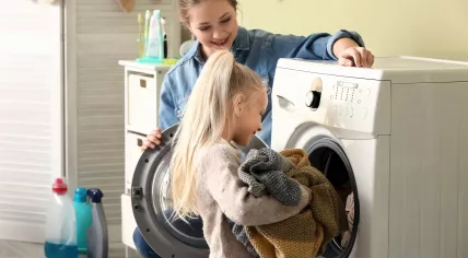 A mother is teaching her daughter how to do laundry