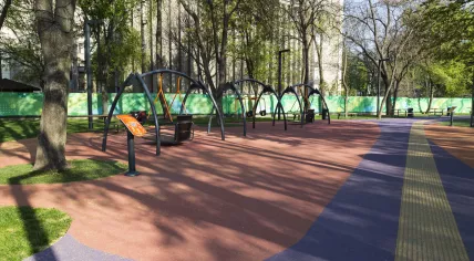 Inclusive playground with broad, textured pathways for visually impaired and swings that can be used by wheelchair users