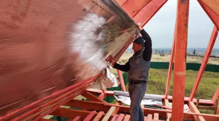 A worker is insulating an attic.