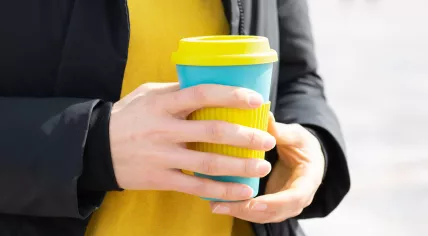 Woman holding a reusable travel mug for coffee