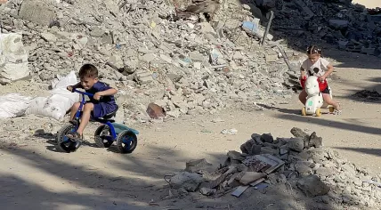 Children bike through rubble in Gaza.