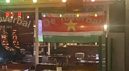 The flag of Suriname hangs in the window of De Toverbal, a café in Amsterdam-Oost. 18 Nov. 2025
