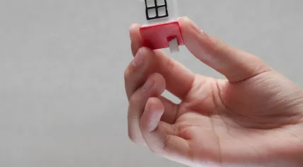 A hand holding a tiny, toy house