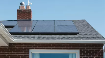 Solar Panels on the roof of brick home with Adirondack garden chairs in front of a window. 2019