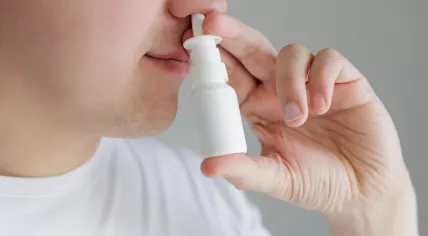 Close up of a young man using nasal spray