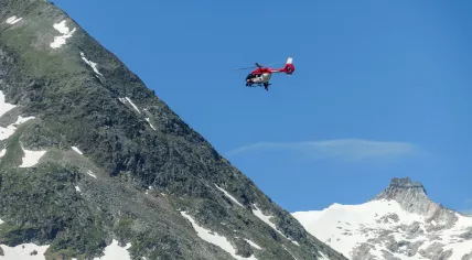 An Austrian rescue helicopter flying above a snowy mountain