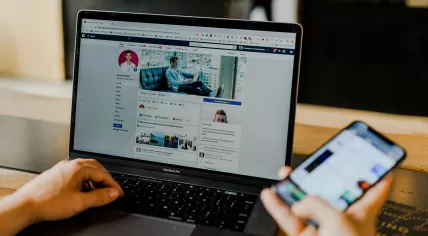 A person using Facebook on a laptop and a smartphone. 2019