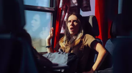 A woman on a train is startled by something.